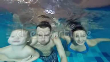 一家人正在游泳池里游泳。 成功的关节浸入水中。 一起快乐地在水下游泳..